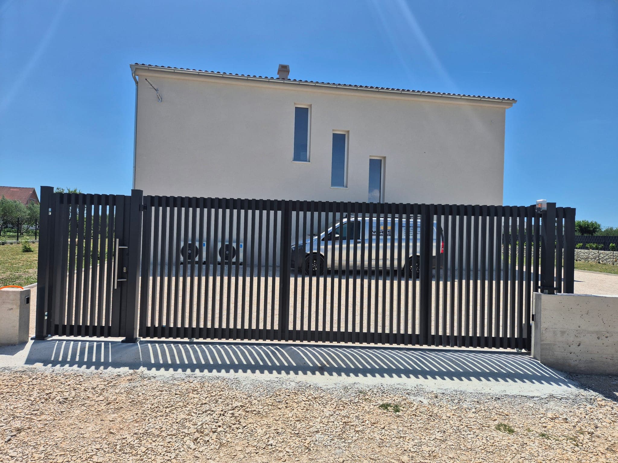 Aluminijska dvorišna klizna vrata s vodilicom i šinom ugrađenom u beton ispred ulaza